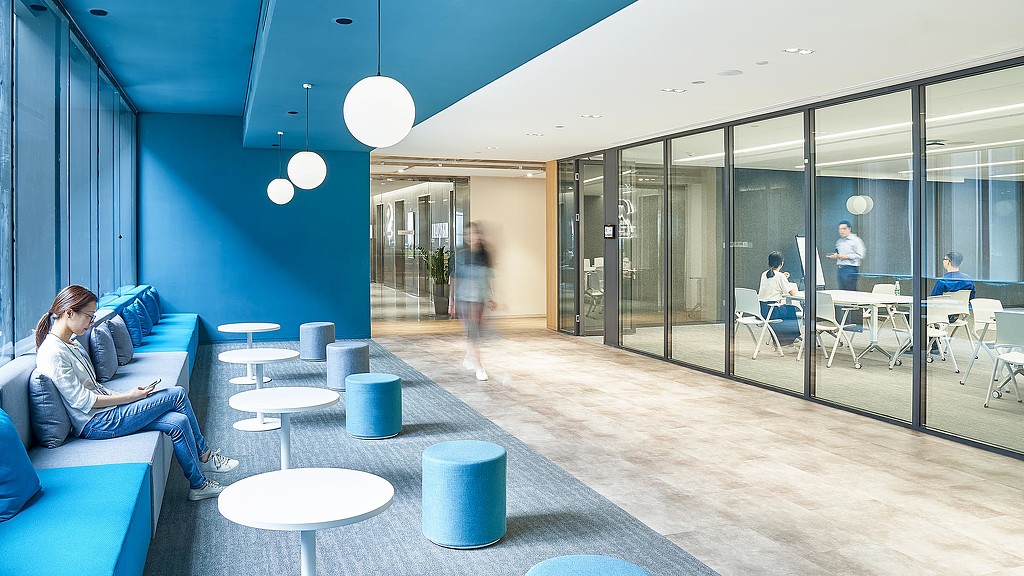 A person sitting on a couch in a room with glass walls.
